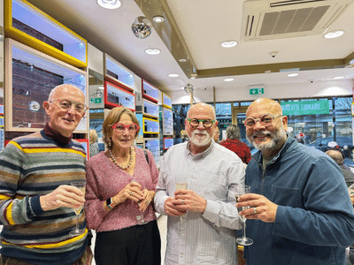 4 happy people wearing brightly coloured glasses holding champagne glasses at a party