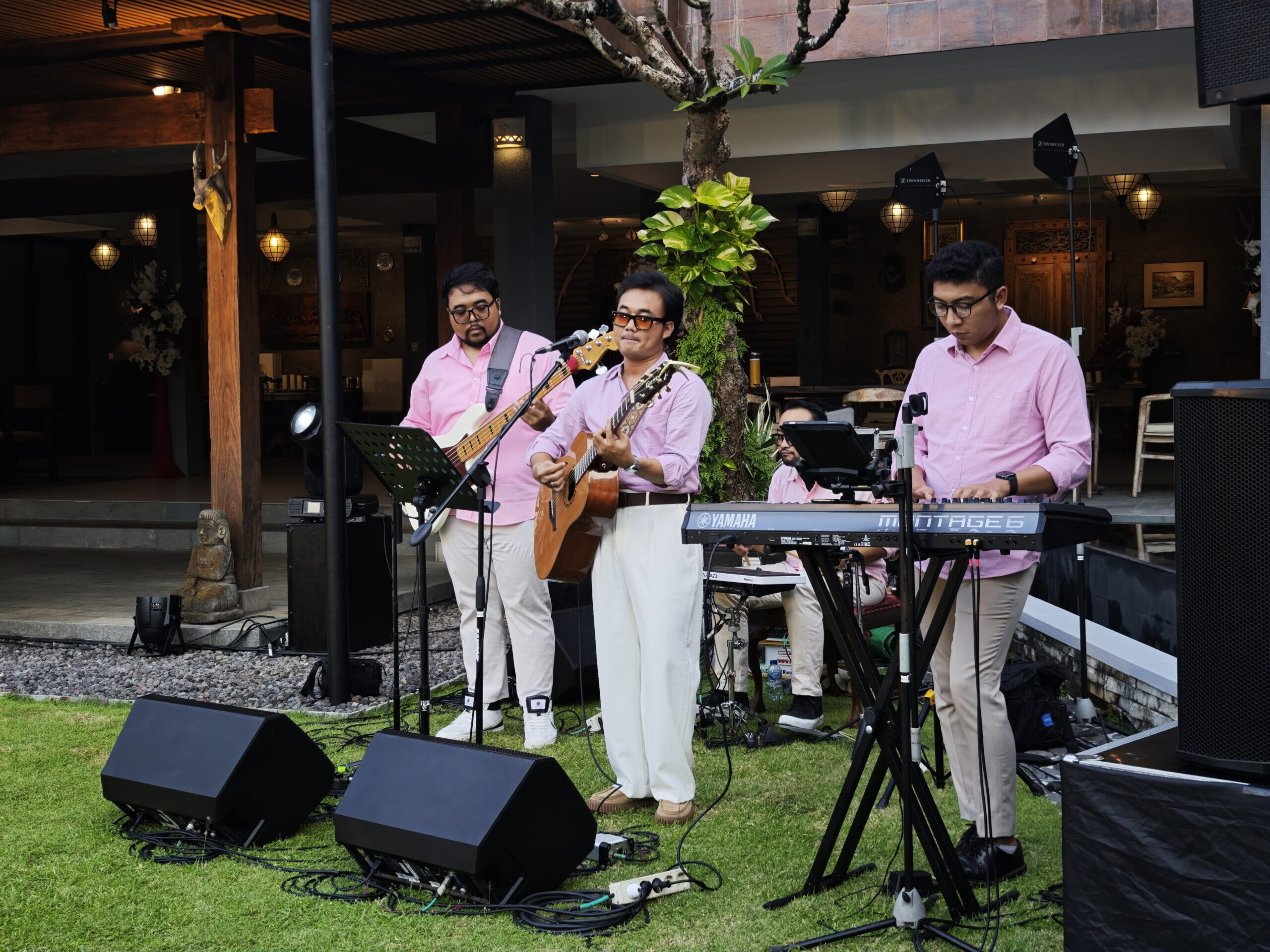 A wedding band playing live, wearing pink shirts and cream linen trousers